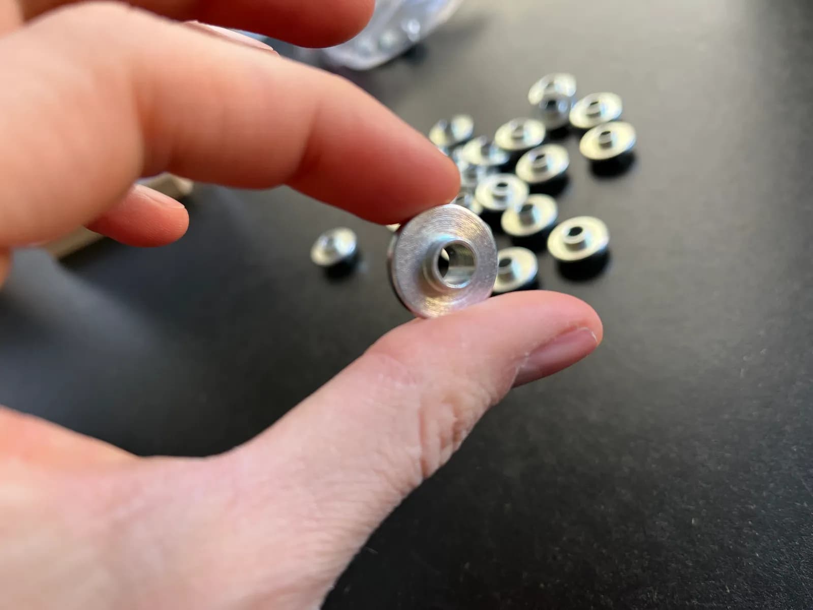Gefertigtes Metall-Präzisionsteil in der Hand, daneben weitere Serienteile
